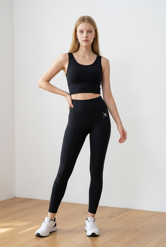 Black high-waisted leggings with a secure fit and side pockets, paired with a matching crop top and white sneakers.