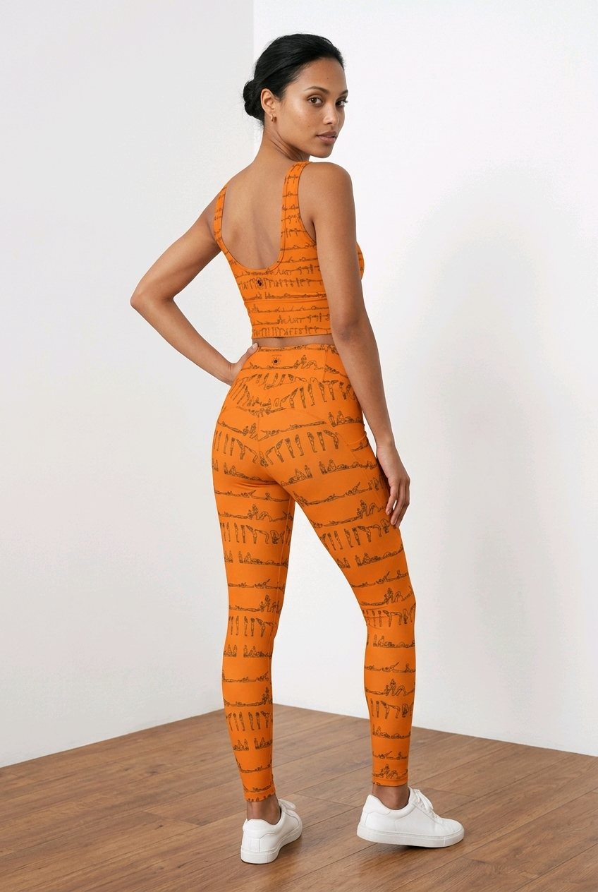 High-rise orange leggings with black yoga posture prints, featuring a snug fit, two side pockets, and paired with a matching crop top.
