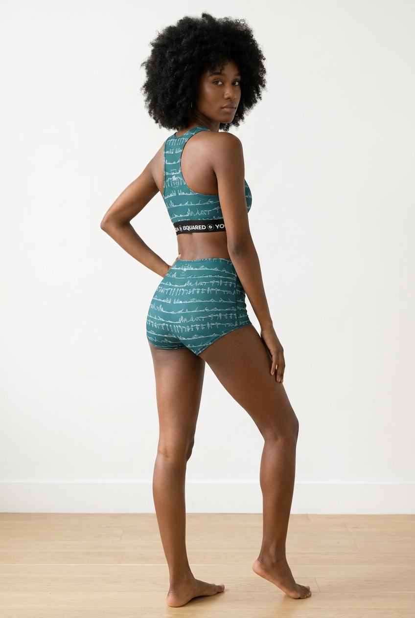 Bikram Ember hot yoga bikini set in teal with white pattern, model wearing top and high-waist shorts, showcasing back view.