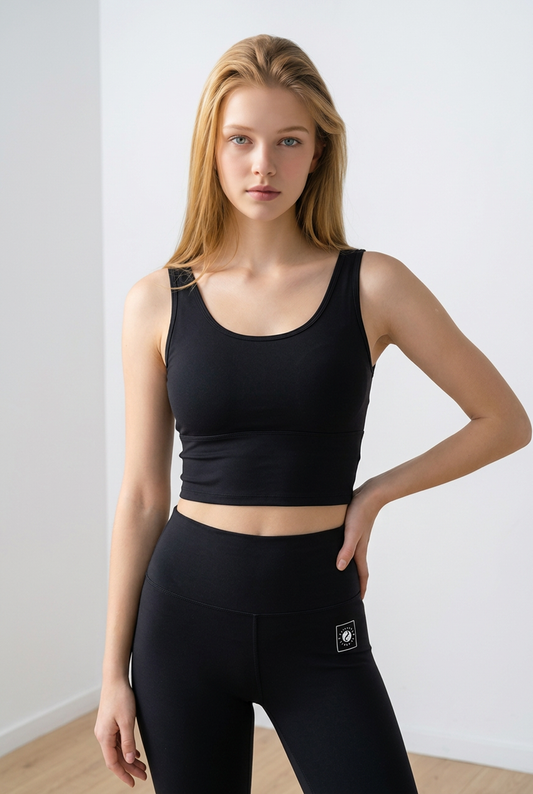 Black iSquared Crop Top with a fitted design, worn with high-waisted leggings, featuring a U-back for support.